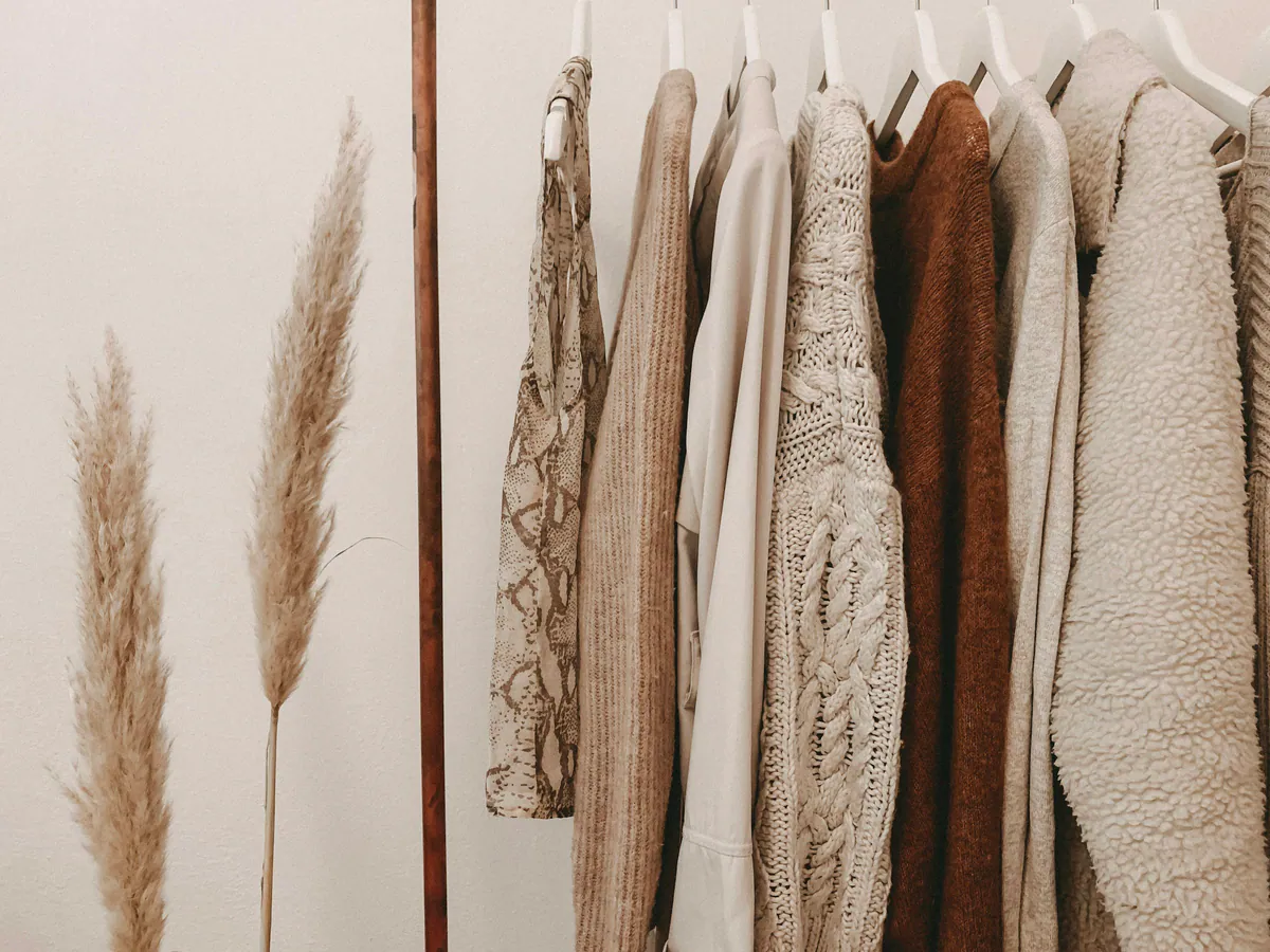 Closet aberto com araras e roupas em tons neutros